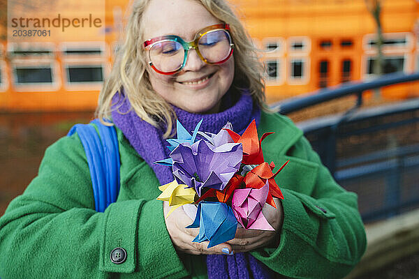 Smiling woman holding colorful origami flowers