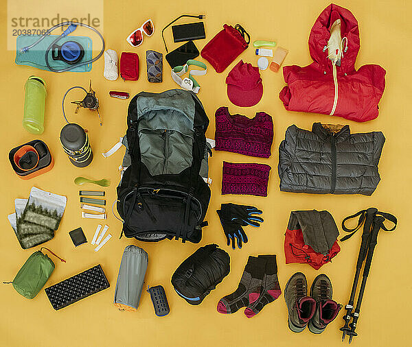 Hiking travel kit arranged on yellow background