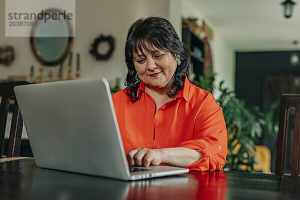 Smiling mature woman using laptop at home