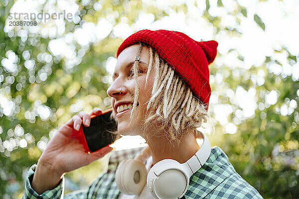 Happy young woman wearing red knit hat and talking on smart phone