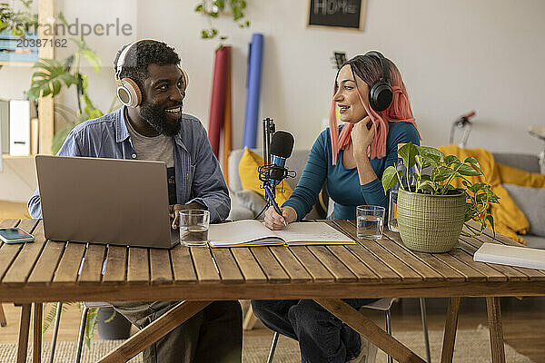 Smiling influencers recording podcast at home