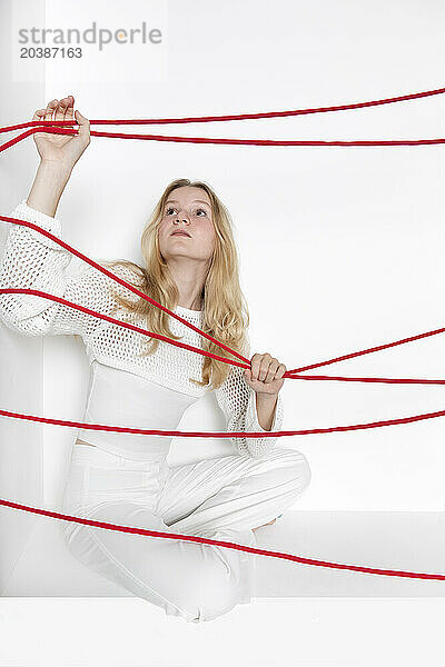 Teenager holding red thread against white background