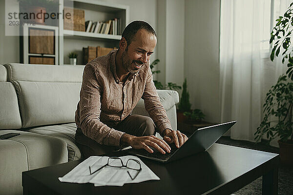 Smiling freelancer working on laptop at home office