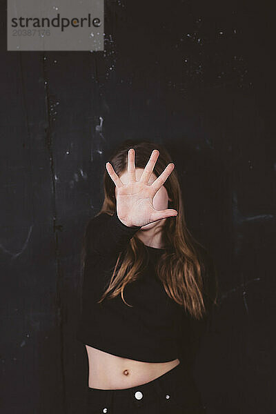 Girl covering face with hand in front of black background