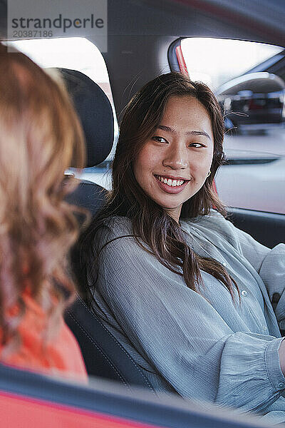 Smiling woman talking with friend in car