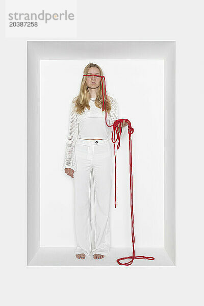 Teenager with thread tied on eyes against white background