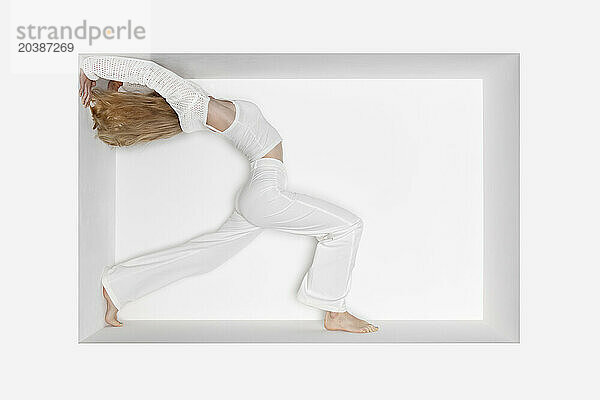 Teenage girl doing handstand against white background