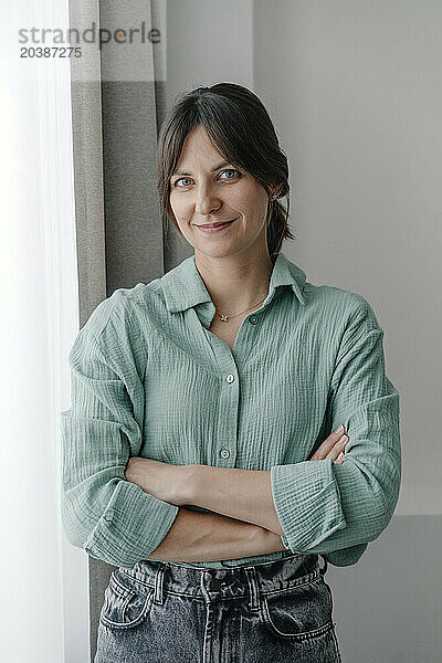 Smiling woman with arms crossed inf front of wall