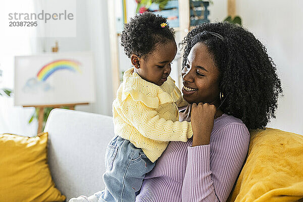 Happy single mother playing enjoying with daughter in living room at home