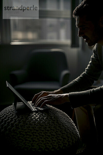 Mature businessman working on tablet PC in dark office