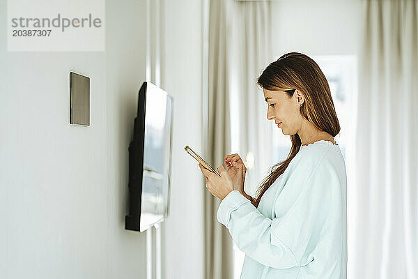 Woman using smart phone standing at home