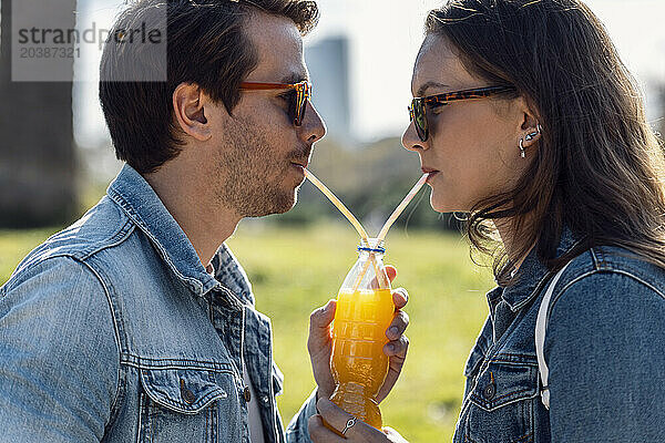 Couple wearing sunglasses and drinking juice through straw