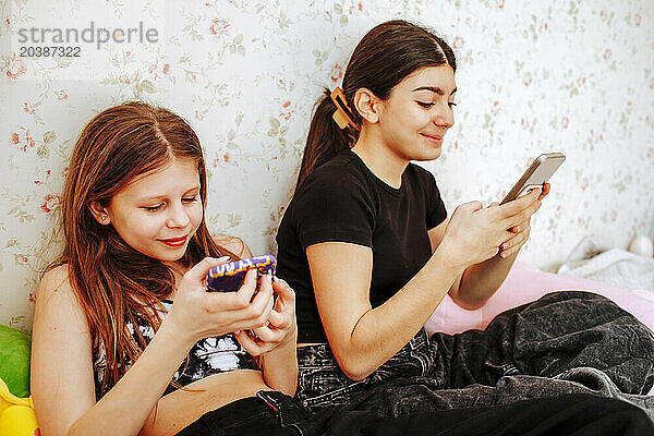 Smiling girls using smart phone at home