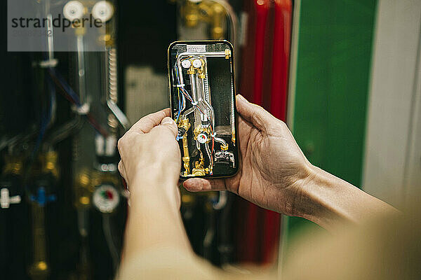 Hands of businesswoman photographing machine through smart phone