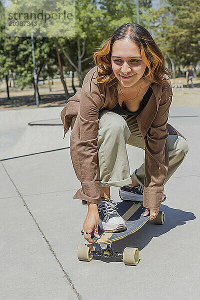 Smiling woman skateboarding on sunny day at park