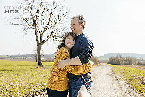 Smiling daughter embracing father standing on footpath