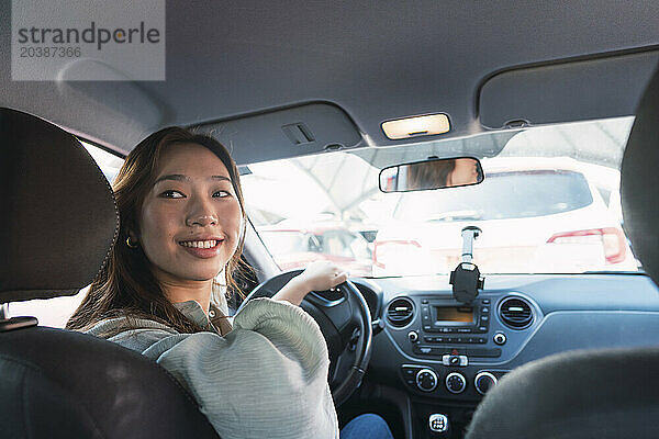 Smiling woman looking over shoulder sitting in car