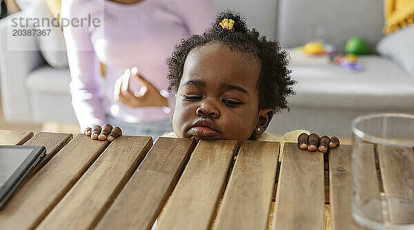 Cute baby girl by wooden table at home