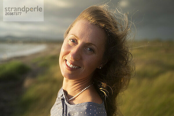 Smiling blond woman enjoying sunset at beach