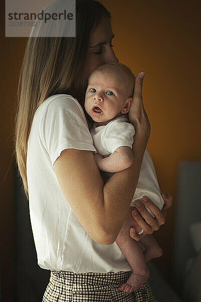 Mother hugging baby boy in arms at home