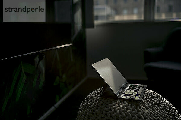 Tablet PC with keyboard kept on hassock in dark office
