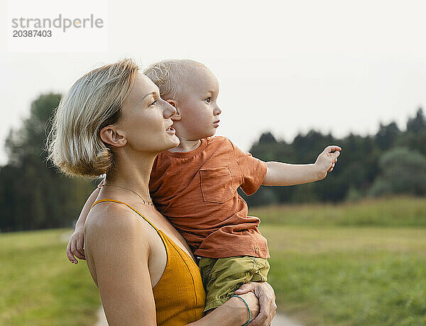 Woman carrying son in arms at meadow