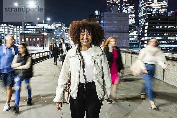 Happy young woman standing in City of London at night
