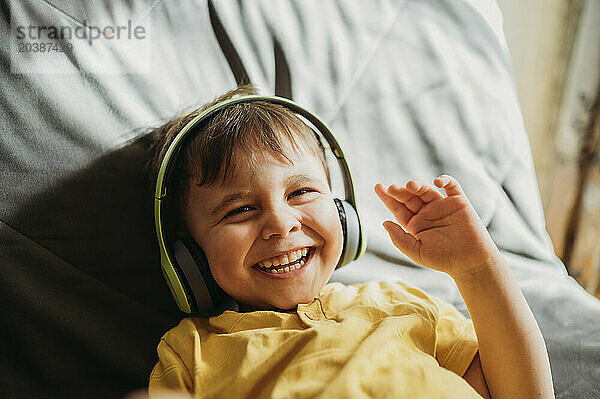 Happy boy wearing wireless headphones at home