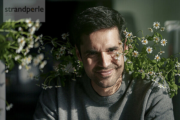 Smiling mature businessman with flowering plants in office