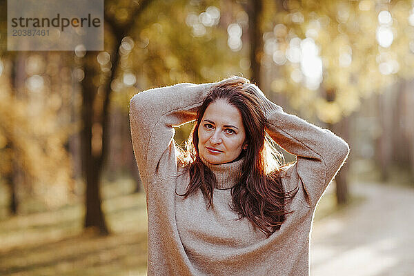 Smiling mature woman with hands in hair at park