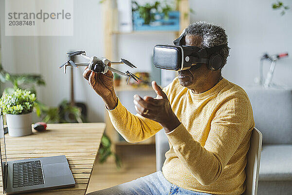 Senior man wearing VR glasses learning to operate drone at home