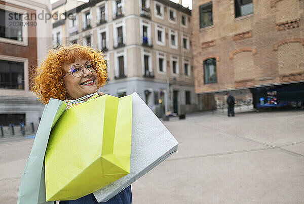 Senior woman with shopping bags on footpath