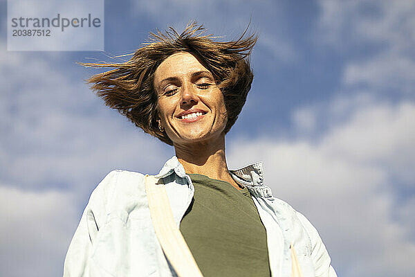 Happy woman with eyes closed under sky