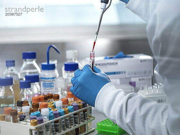 Pathologist pipetting blood sample in test tube at laboratory