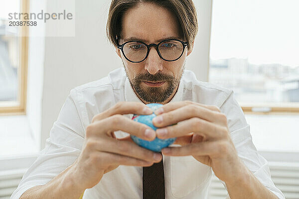 Businessman looking at globe in office