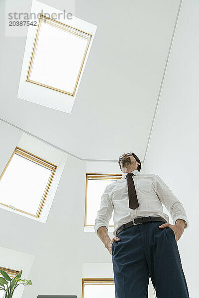 Businessman standing with hands in pockets at minimalist office