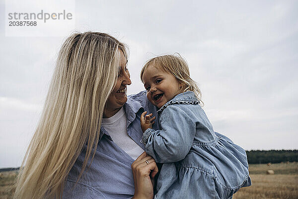 Blond woman playing with daughter under sky