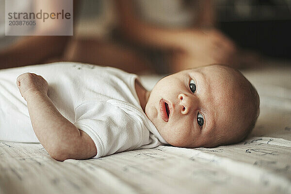 Cute baby boy lying on bed at home