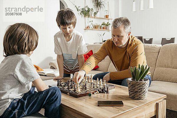 Father playing chess with children at home