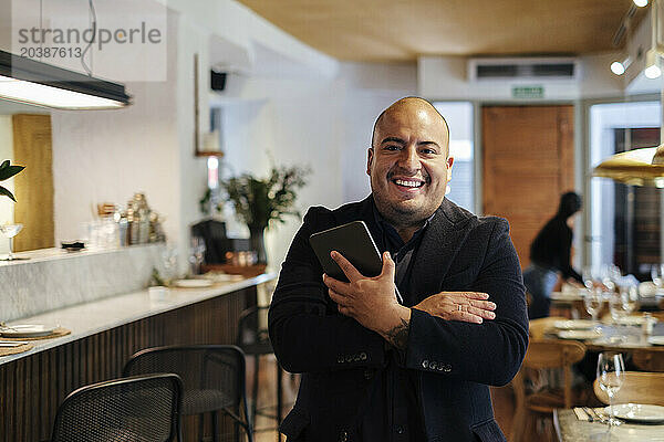 Smiling restaurant owner standing with tablet PC