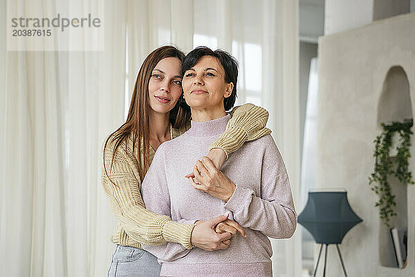 Smiling woman embracing mother at home