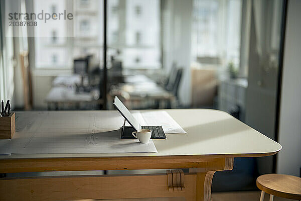 Tablet PC near white coffee cup at desk in office