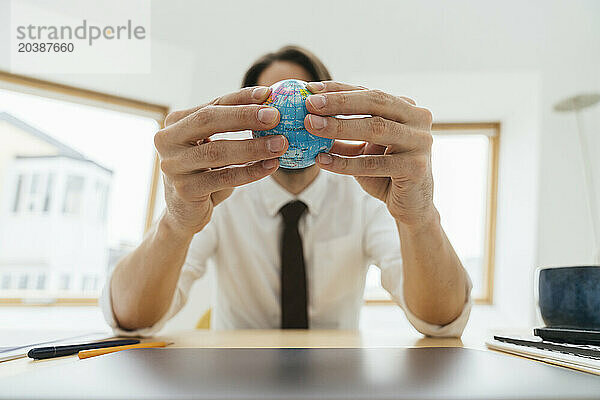 Businessman holding globe at desk in office