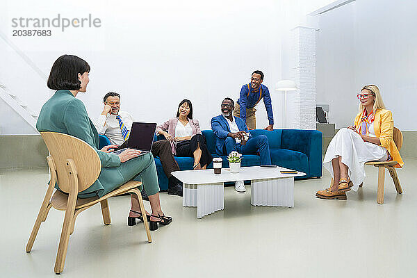 Businesswoman discussing with multi-ethnic colleagues sitting at office