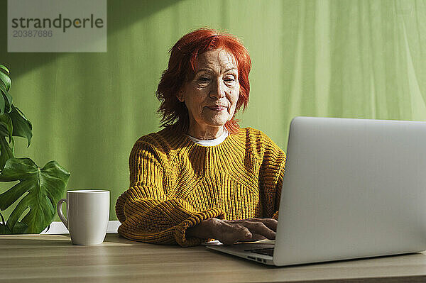 Senior redhead businesswoman using laptop working at home