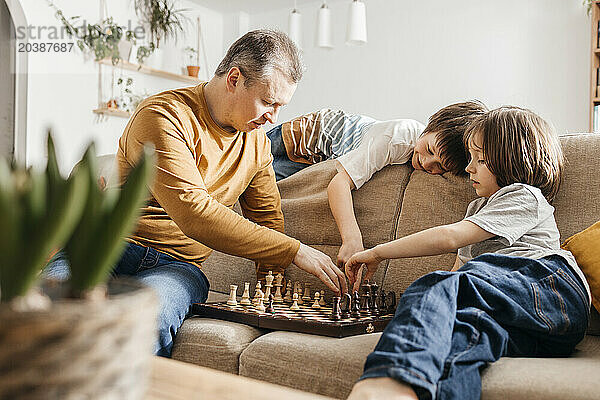 Family playing chess on sofa at home