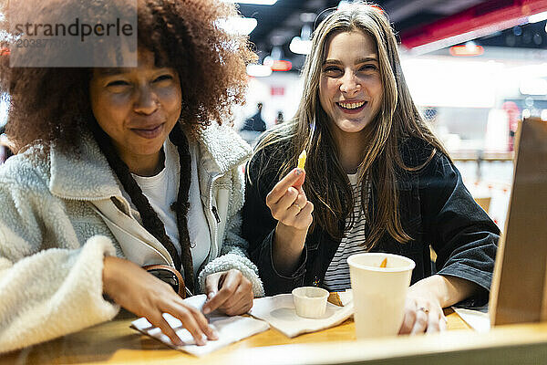 Smiling friends sitting with food in cafe