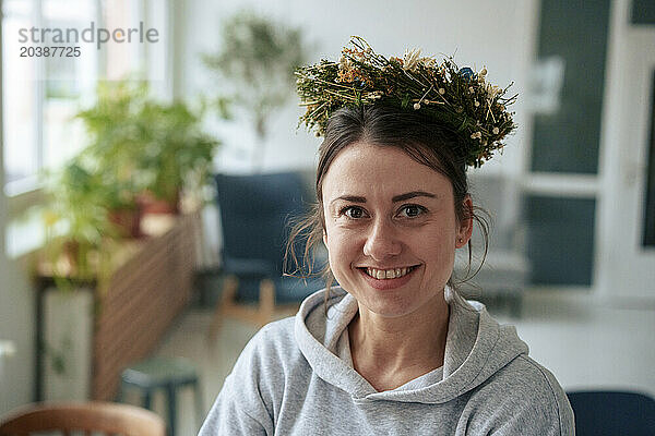 Smiling woman wearing flowers on head at home