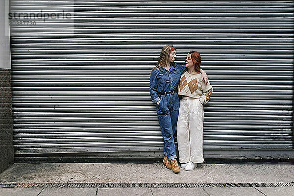 Happy friends talking to each other in front of shutter