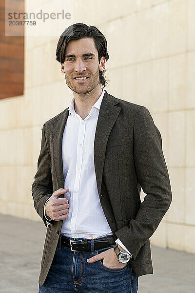 Confident young businessman in blazer on footpath